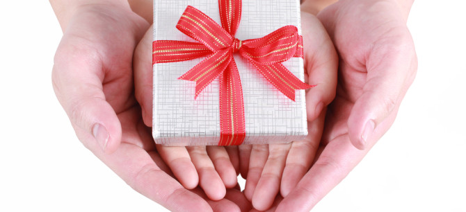 Hands holding a gift with a red bow.