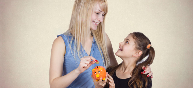 Mother and daughter putting money in a piggy bank