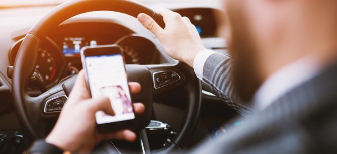 man driving while texting on a mobile phone